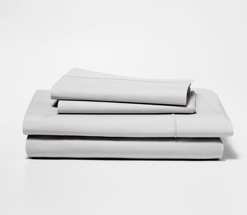 Folded set of two Ash Grey Percale Pillow Cases on top of a folded Percale Fitted Sheet and Flat Sheet.