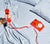 Person holding red vintage telephone over bed dressed with Slate Blue Percale bedding.